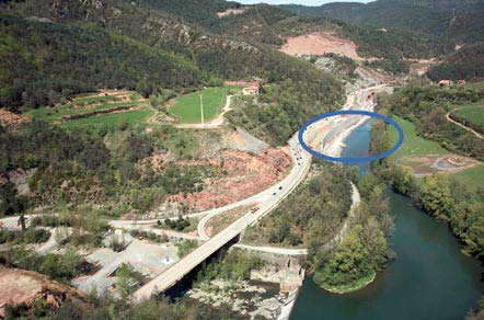 Aerial photograph of the wall under construction and of settling basins aligned in a crescent shape row located on the opposite bank of the River Ter.